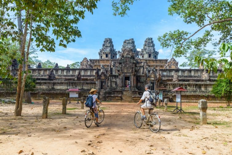 Couple de touristes faisant du vélo autour du temple d'Angkor, au Cambodge.