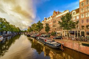 Vue pittoresque des canaux d'Amsterdam avec des bateaux et des maisons traditionnelles en arrière-plan