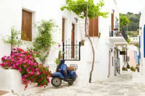 scooter garé sur une route bordée de bâtiments blancs à Paros