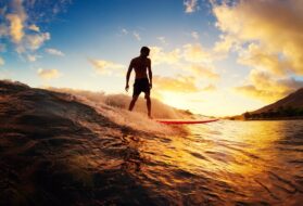surfeur prenant une vague au coucher de soleil