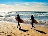 Couple of surfers walking on the ocean beach. Sagres, Algarve, Portrugal