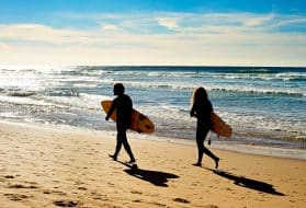 Couple of surfers walking on the ocean beach. Sagres, Algarve, Portrugal