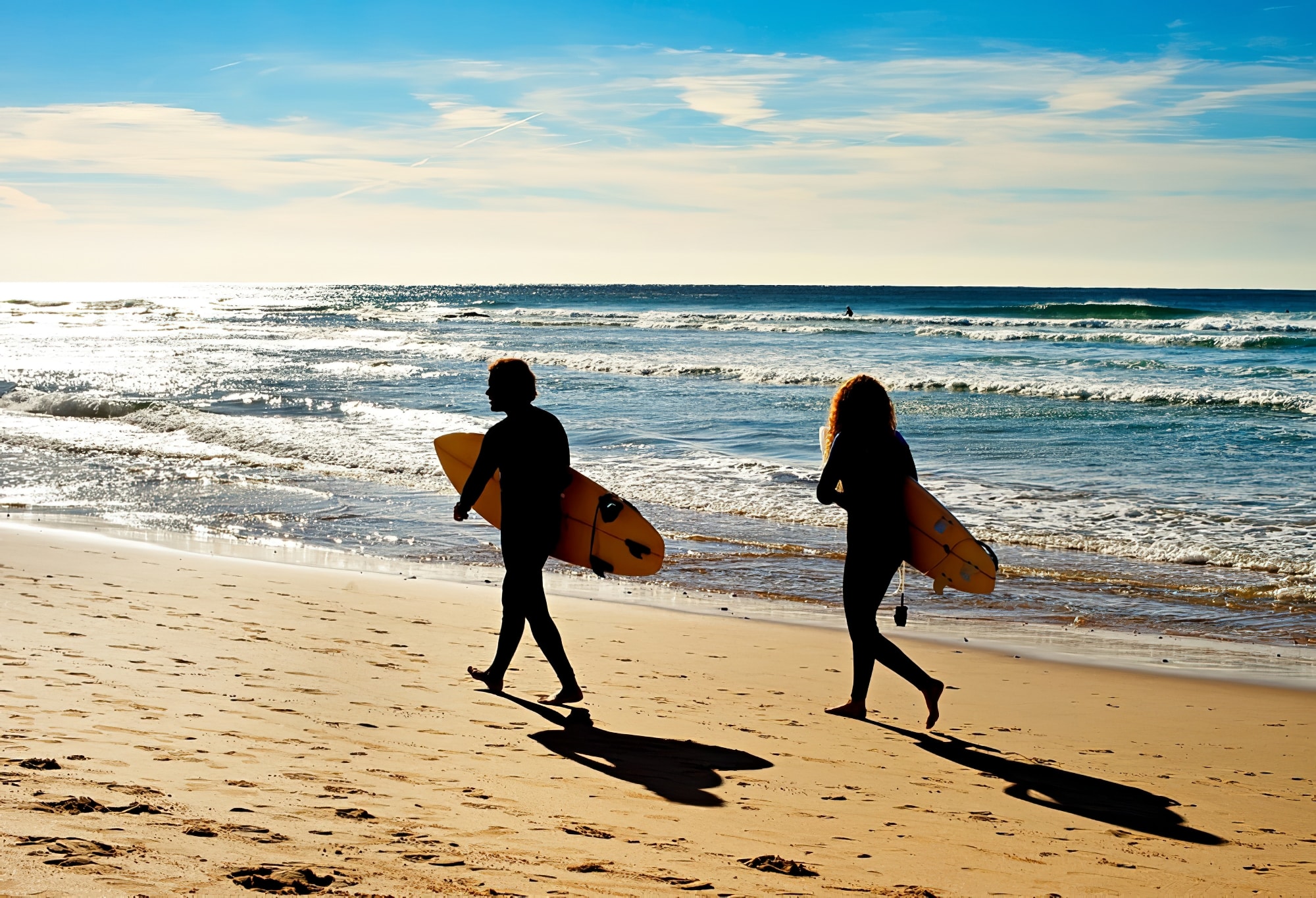 Couple of surfers walking on the ocean beach. Sagres, Algarve, Portrugal