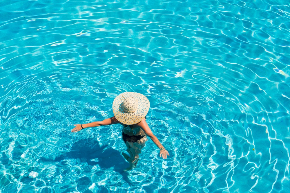 Jeune femme en bikini portant un chapeau de paille à la piscine