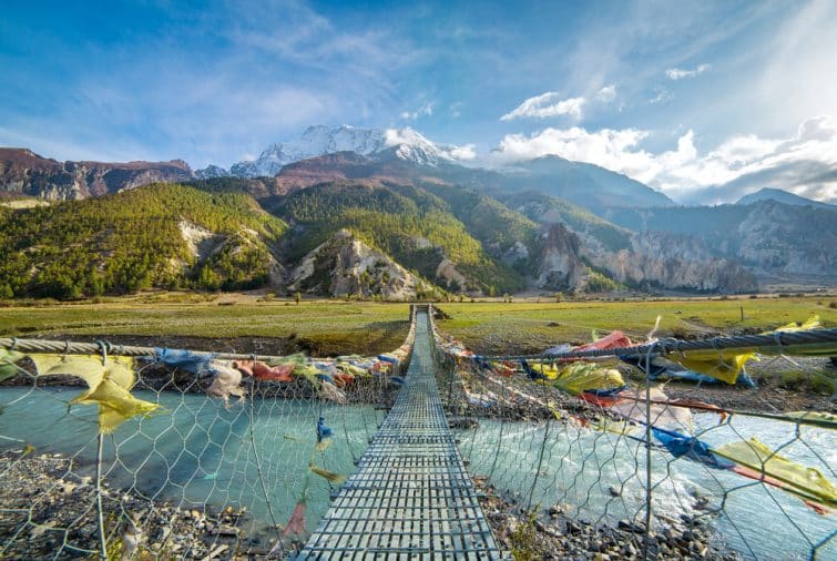 Pont de suspension avec drapeaux bouddhistes pour la prière sur le circuit d'Annapurna au Népal. Shangri-la