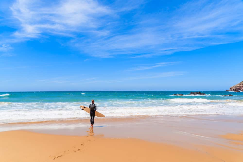 Surfer sur la plage de Praia do Amado par beau temps, région de l'Algarve, Portugal  