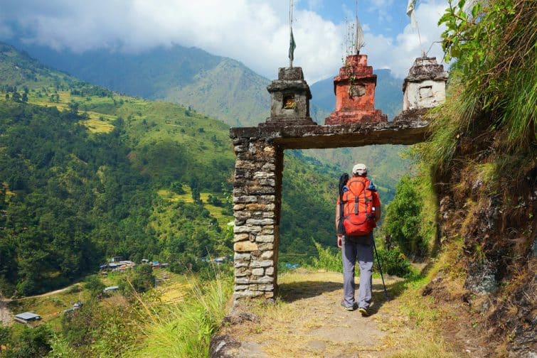 Un homme, entre la porte du village népalais dans la vallée sur le circuit d'Annapurna Trek