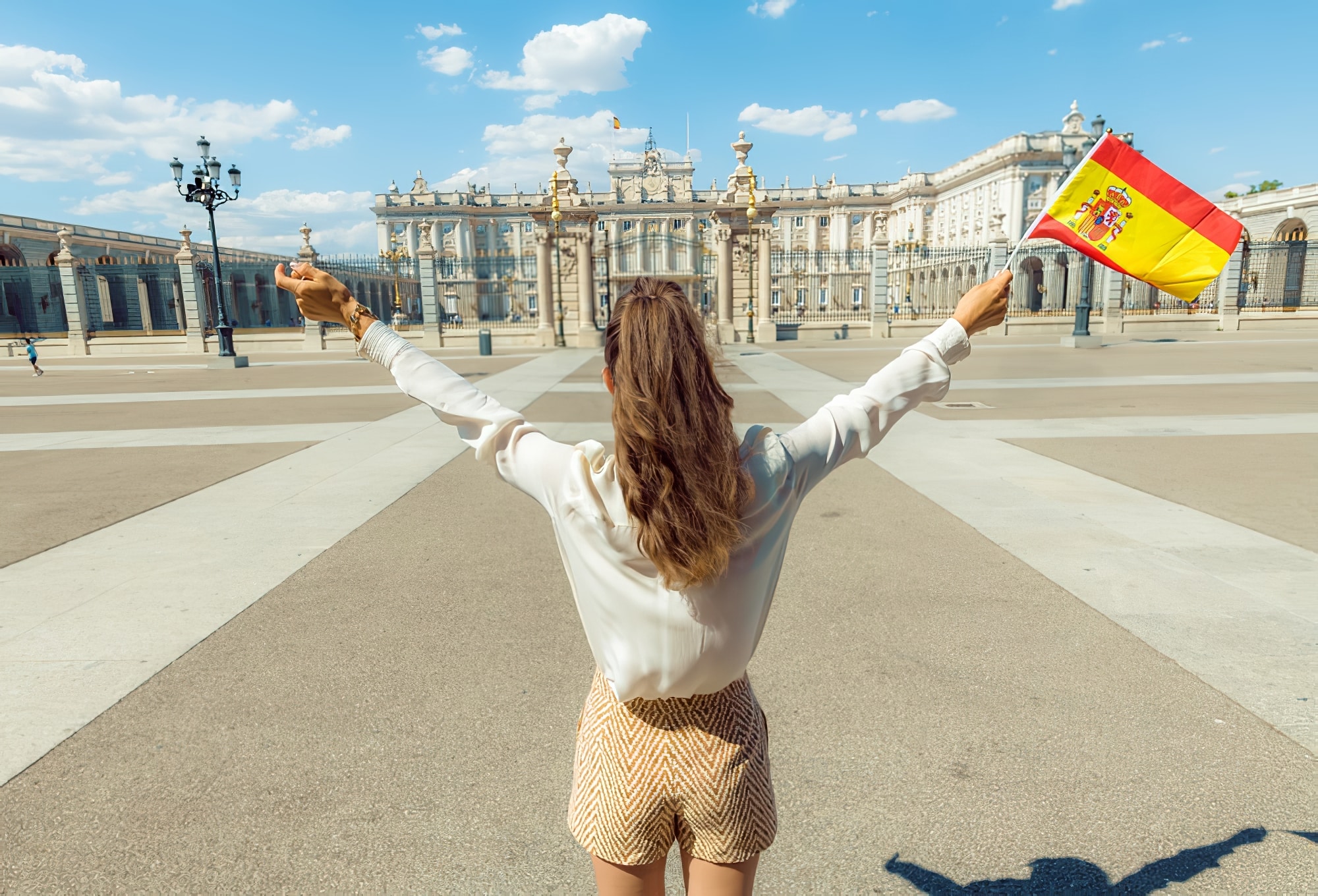 Vue d'une femme derrière la mode avec le drapeau espagnol se réjouissant contre le Palais Royal