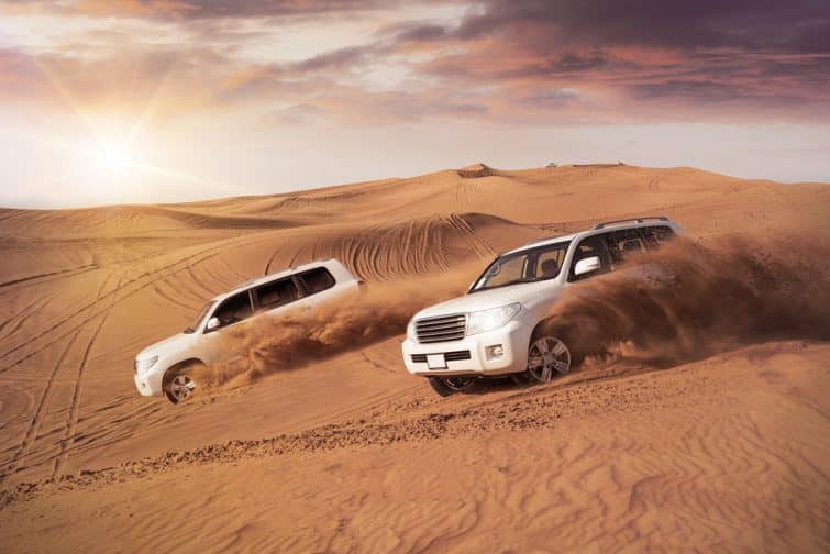 deux véhicules 4x4 se balançant côte à côte dans les dunes du désert le soir au soleil