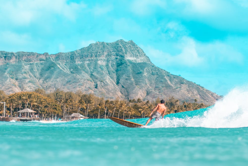 Surfer sur une vague devant Diamond Head à Waikiki.
