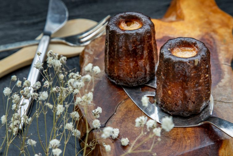 Cannelés de Bordeaux : petite pâtisserie au rhum et à la vanille sur une assiette en bois