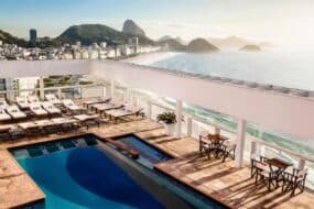 Vue de l'hôtel Copacabana avec piscine et palmiers au bord de la mer