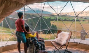 Couple regardant la nature depuis des tentes de geo dome. Vert, bleu, arrière-plan orange. Confortable, camping, glamour, vacances, vacances, concept de vie romantique. Cabine extérieure, arrière-plan scénique.Nouvelle-Zélande