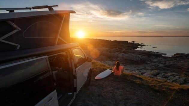 surfeuse à côté de son van devant le coucher de soleil