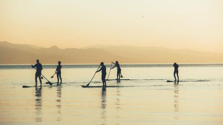 Groupe de personnes en stand up paddle à Barcelone au lever du soleil