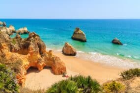 Plage avec des rochers et falaises dorées dans la ville d'Alvor, Algarve, Portugal