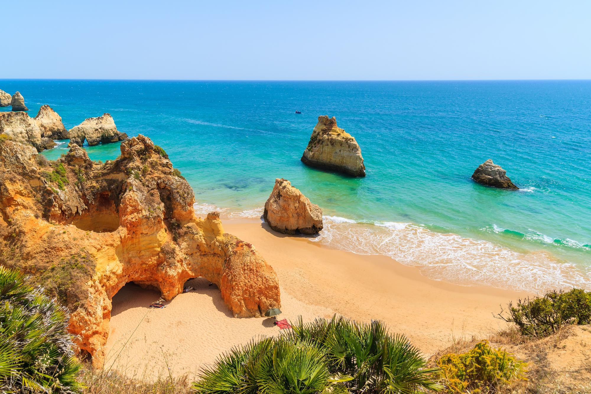 Plage avec des rochers et falaises dorées dans la ville d'Alvor, Algarve, Portugal