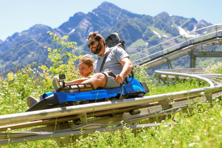 Père et enfant en luge sur rail à la montagne