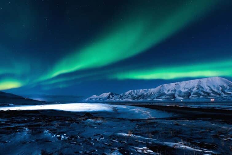 Aurores boréales illuminant le ciel nocturne au-dessus des montagnes de Camp Barentz, Norvège