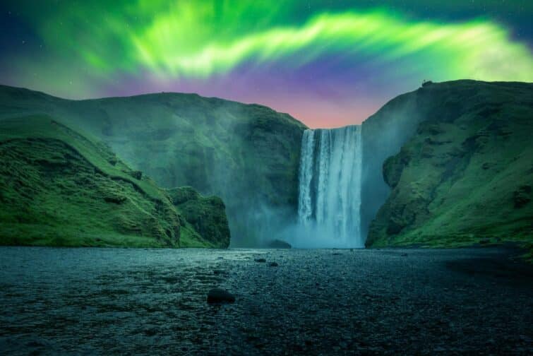 Aurores boréales vertes derrière la célèbre cascade de Skogafoss en Islande