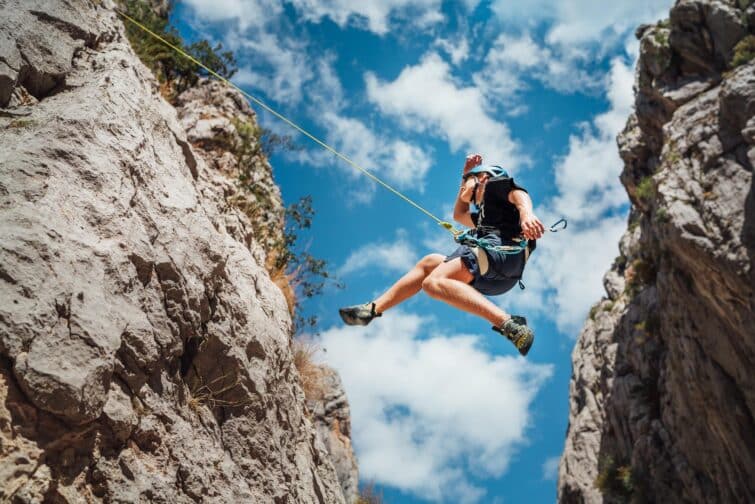 Grimpeur adolescent en casque de protection sautant dans le canyon de Paklenica, Croatie