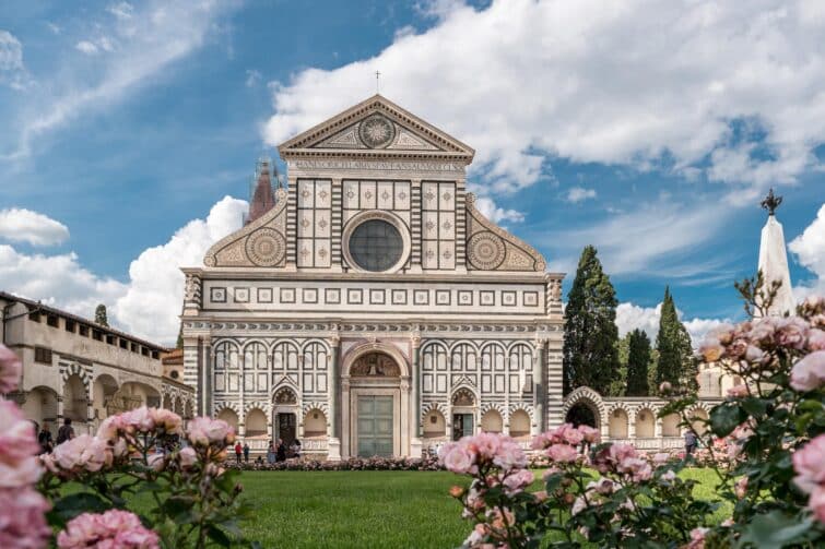 Vue de la Basilique Santa Maria Novella à Florence, Italie, montrant l'architecture Renaissance avec des touristes et un ciel bleu clair.