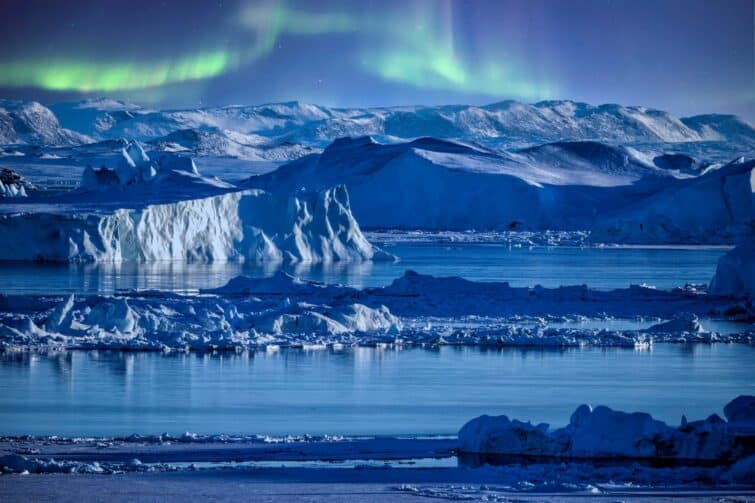 Aurores boréales illuminant le ciel au-dessus des icebergs dans la baie de Disko, Groenland lors d'une croisière