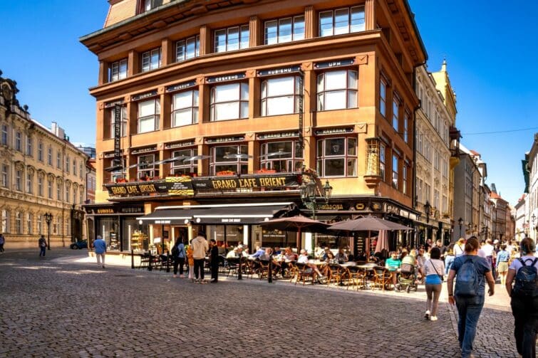 Grand Café Orient à Prague, intérieur élégant avec des visiteurs en discussion autour de café en juin 2023