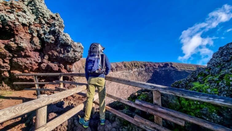 Homme actif avec un sac à dos debout sur une barrière regardant le paysage du cratère du Vésuve à Naples