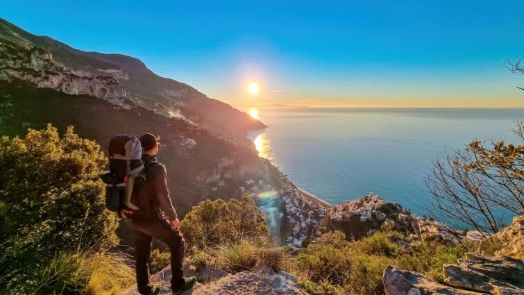 Homme actif avec un sac à dos regardant le lever du soleil en randonnée sur le Sentier des Dieux, Italie