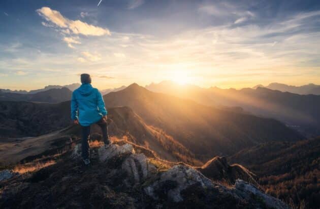 Homme sur une colline de pierre devant un paysage montagneux époustouflant dans les Dolomites, Italie