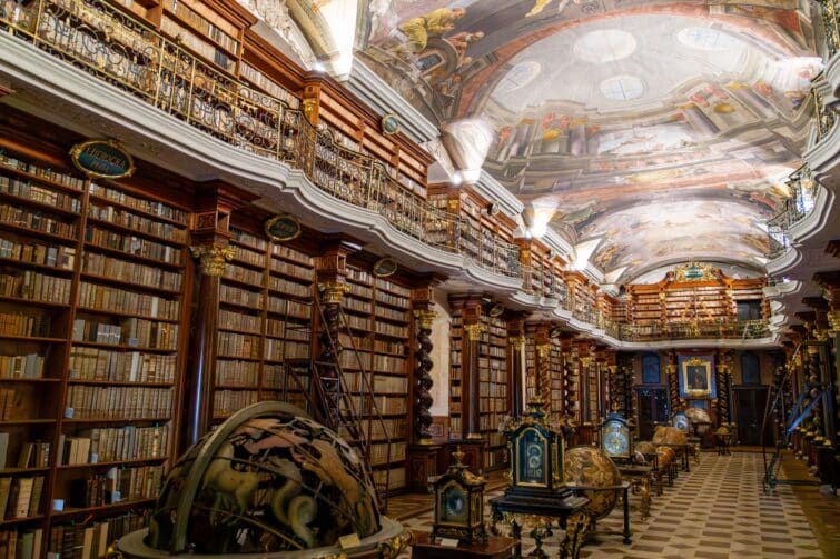 Intérieur de la bibliothèque du Clementinum à Prague, remplie de livres anciens et ornée de fresques au plafond