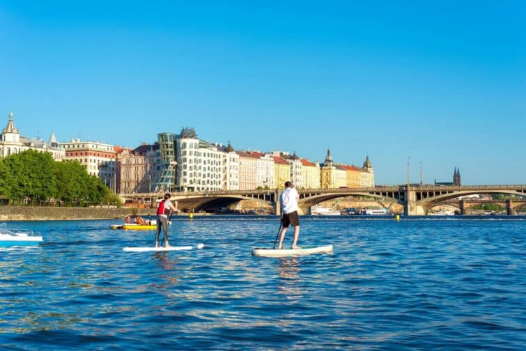 Personne faisant du paddle sur la rivière Vltava avec vue sur Prague en arrière-plan