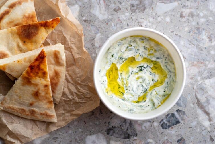 Sauce tzatziki grecque traditionnelle faite de yaourt, concombre et ail, garnie de menthe, présentée dans un bol blanc