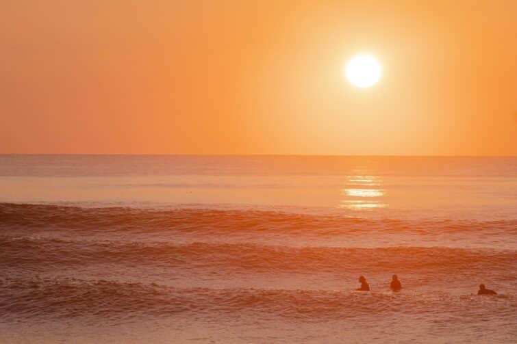 Surfeurs à Hossegor, France, au coucher du soleil