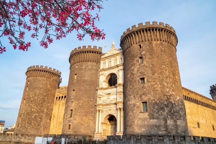 Vue du Château Neuf (Maschio Angioino) à Naples, Italie, un château médiéval avec une architecture impressionnante et un ciel bleu clair.