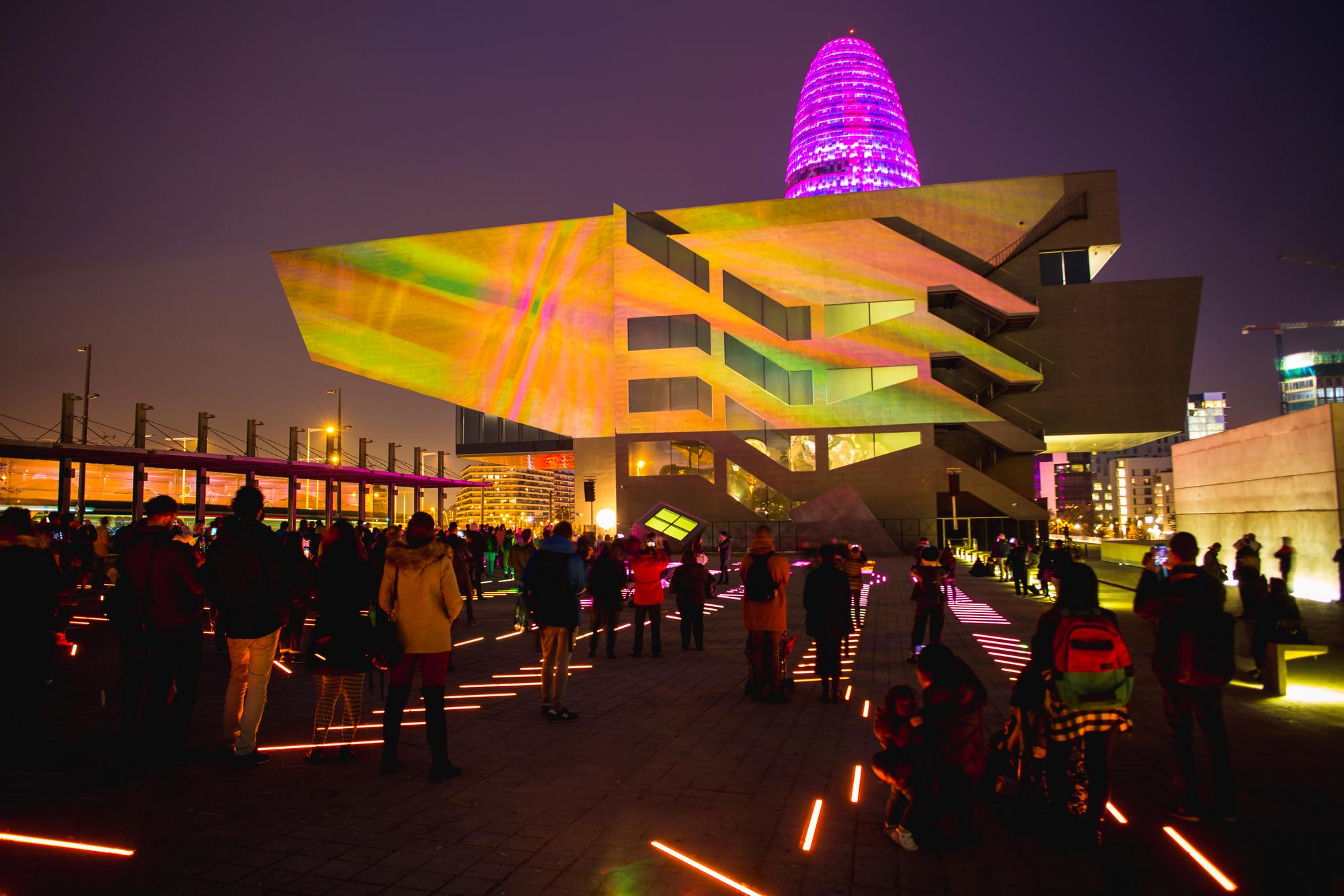 Vue nocturne éclairée de Poblenou, Barcelone, montrant des rues animées et l'architecture moderne