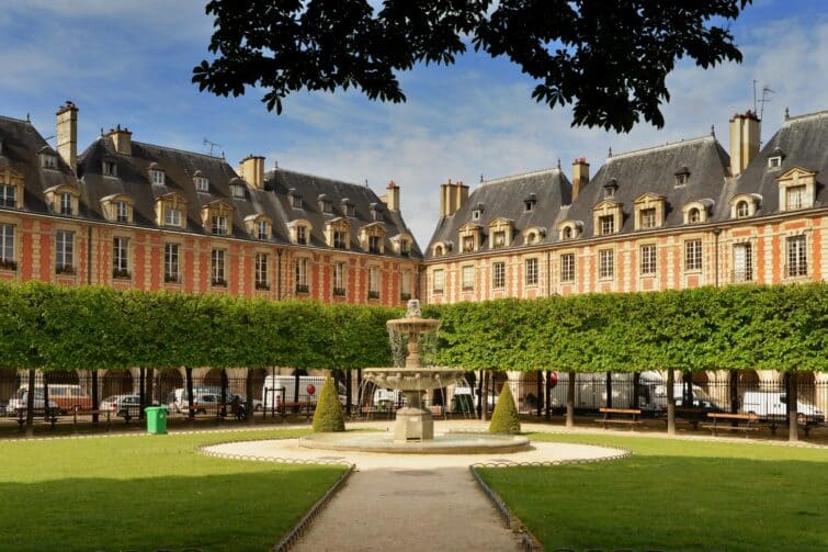 Vue pittoresque de la Place des Vosges à Paris, montrant l'architecture historique et les jardins verdoyants.