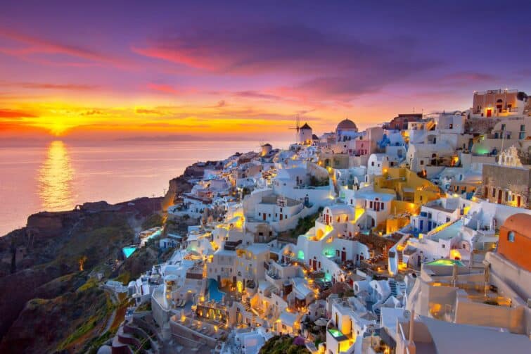 Vue panoramique d'Oia, ville pittoresque sur l'île de Santorin, Grèce, avec ses maisons blanches typiques et églises à dômes bleus surplombant la mer Egée