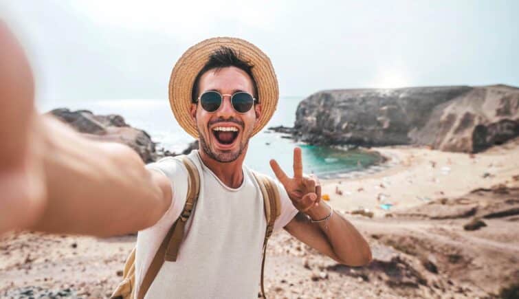 Homme élégant portant un chapeau et des lunettes de soleil prenant un selfie