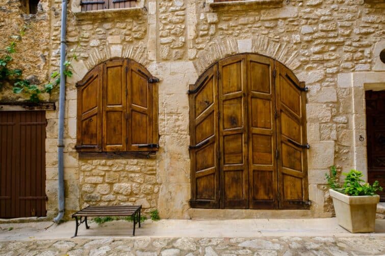 Façade de vieille maison avec porte en bois et volets à Simiane-la-Rotonde