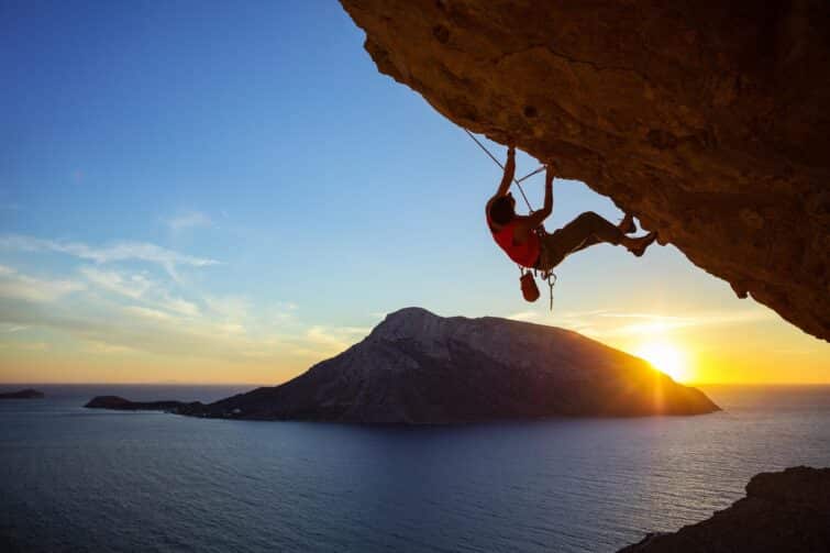 Homme pratiquant l'escalade sportive à Kalymnos, Grèce lors du coucher du soleil