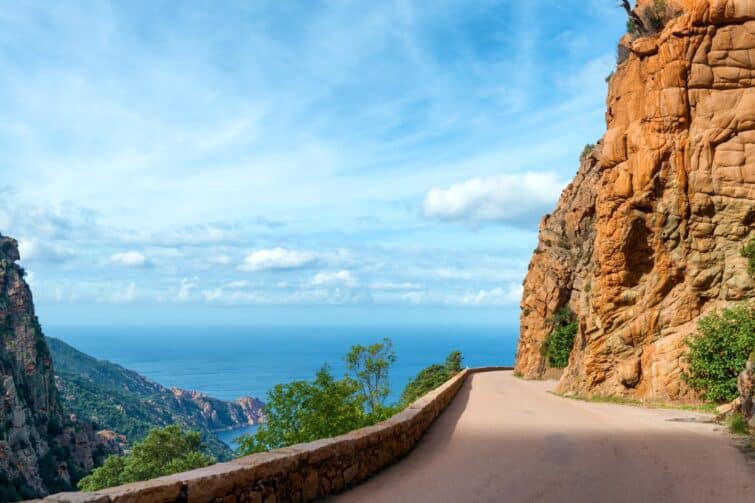 Route sinueuse des calanques de Piana avec vue sur des criques rocheuses et la mer Méditerranée