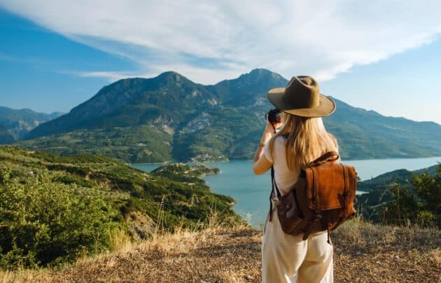 femme photographe avec grand sac à dos prenant une photo en voyage