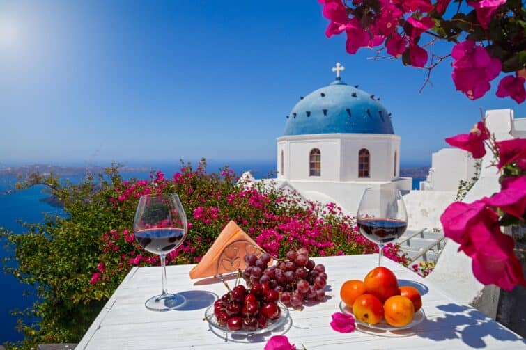 Deux verres de vin rouge avec des fruits sur une table à Santorin face à la mer Égée