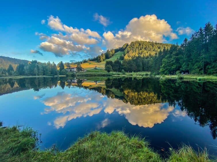 Lac de Lispach avec reflets des nuages sur l'eau lors d'une balade paisible