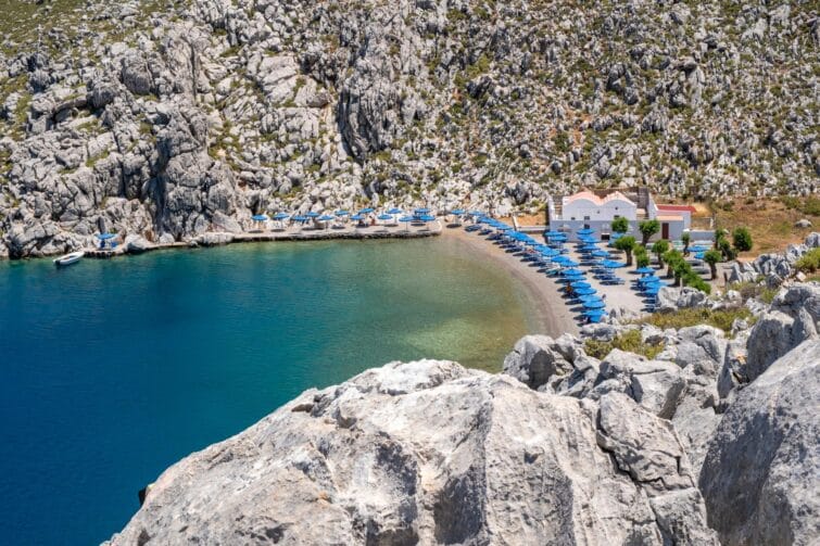 Plage tranquille de Saint-Nicolas à Symi avec eau cristalline et bateaux amarrés