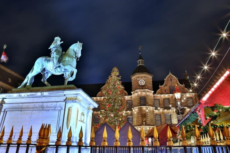 Marché de Noël à Düsseldorf devant l'hôtel de ville historique, avec stands illuminés et divers visiteurs