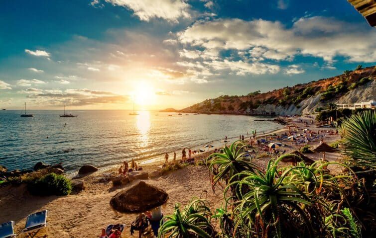 Coucher de soleil à la plage de Cala d'Hort à Ibiza, avec des personnes profitant du soleil et de la mer