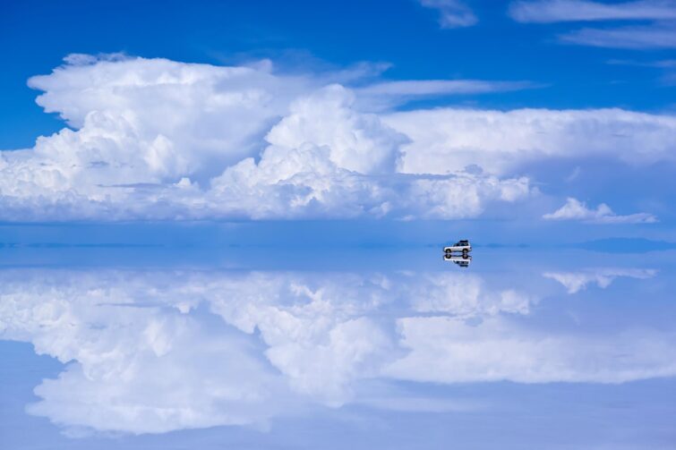 4WD car driving on mirror surface of Salar de Uyuni, Bolivia